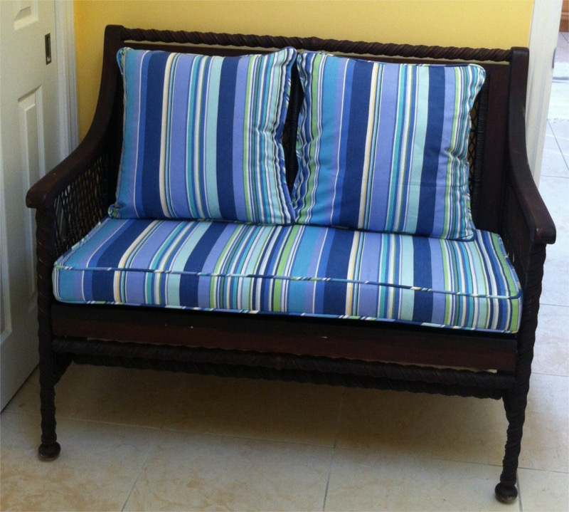 Blue, green and white striped cushions and pillows on wicker love seat
