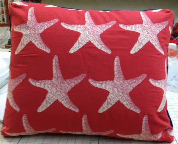 Square throw pillow in red fabric with stenciled textured sea stars