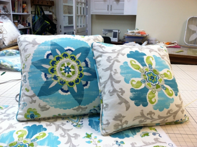 Two throw pillows with piped edging with centered design from same fabric but different pattern to each