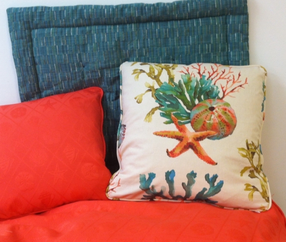Three throw pillows of complementary colors; two with piping and one with inset stitching