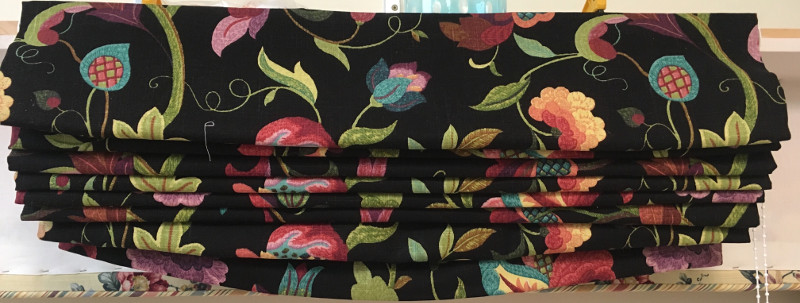 Closeup of gathered fabric of roman shade with black background and colorful flowers