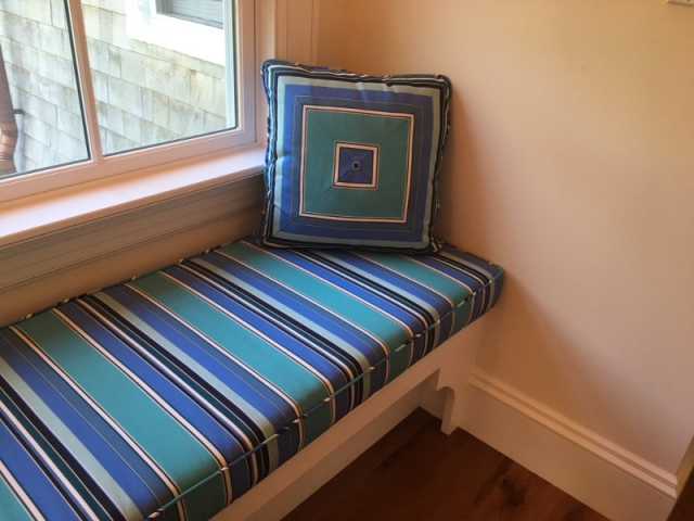 Striped window seat cushion with piped edging and matched square pillow of four perfectly-aligned panels