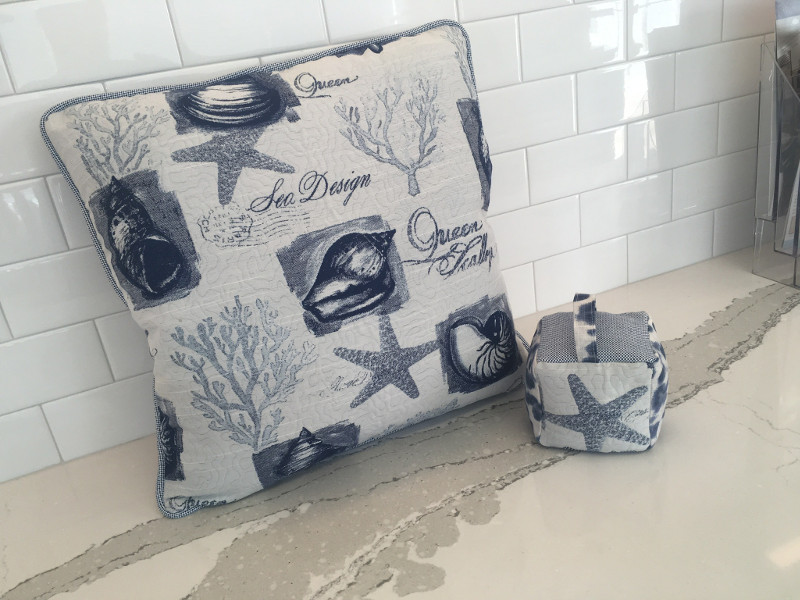 Patterned throw pillow with piped edging and matching fabric doorstop